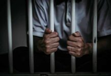 person gripping prison bars
