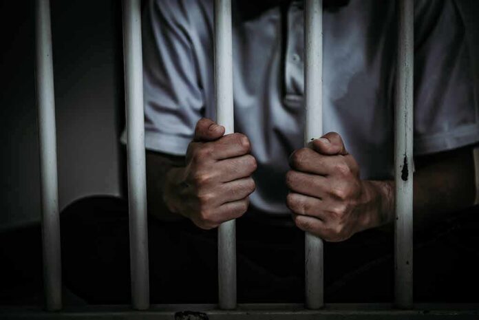 person gripping prison bars