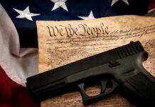 DOJ Reopens Path To Restore Gun Rights Handgun on U.S. Constitution with American flag backdrop