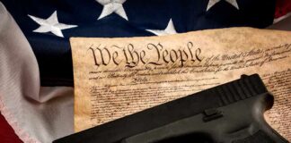 Handgun on U.S. Constitution with American flag backdrop