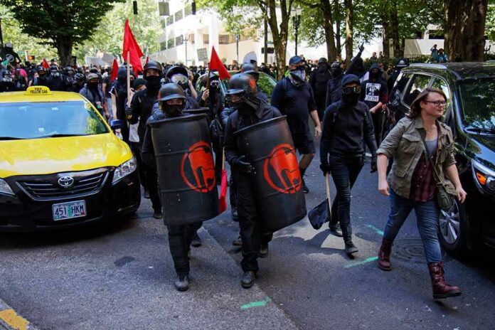 shutterstock_1246503550 masked protesters march with shields on a city street