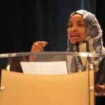 Woman in hijab speaking at a podium
