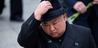 man in black coat adjusting a black hat