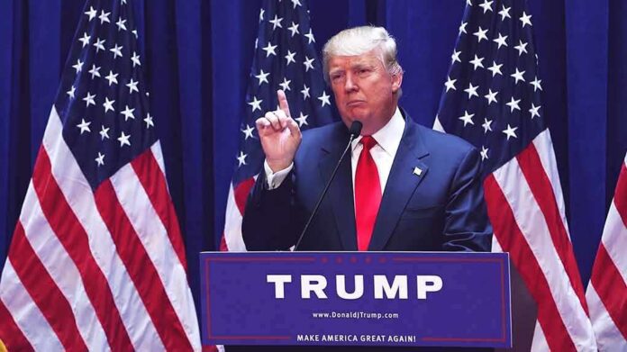 shutterstock_1456399979 man in suit speaking at podium with multiple American flags