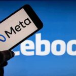 Smartphone showing Meta logo against blurred Facebook background