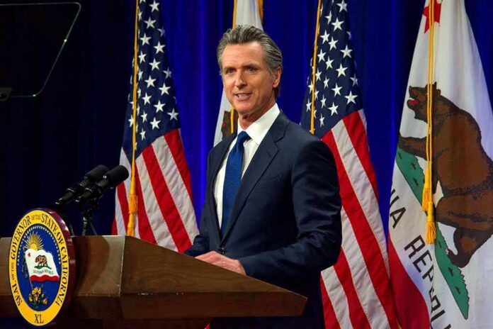 shutterstock_2137542759 Man in suit speaking at a podium with American and California flags