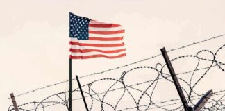 American flag above barbed wire fence