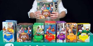 Girl Scout displays assorted cookie boxes on a table