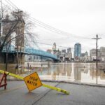 Flooded riverfront with bridge and city skyline