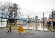 Flooded riverfront with bridge and city skyline