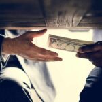 Fraud Cracks Epstein Payout Program Hands exchanging cash under a table