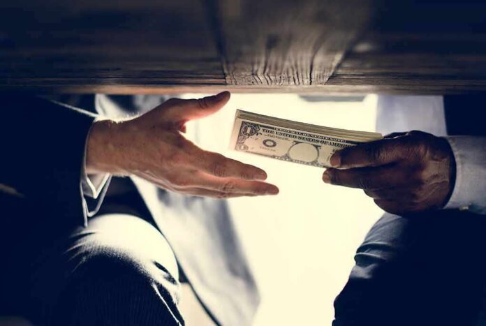 Hands exchanging cash under a table