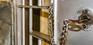 Prison cell door with key and chain in lock