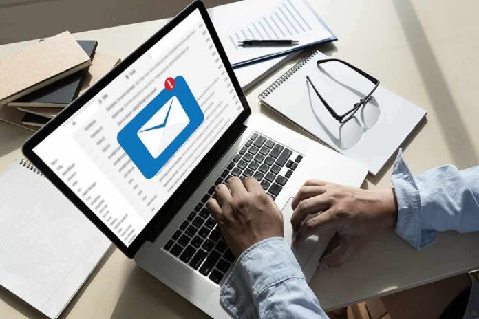 Hands typing on laptop with new email notification icon on screen