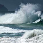 Crashing ocean waves against the shore under a cloudy sky