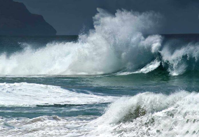 Crashing ocean waves against the shore under a cloudy sky