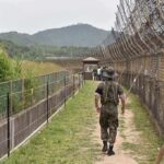 Soldier walking along a fenced border path