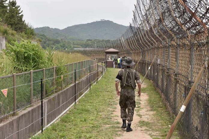 shutterstock_1478361905 Soldier walking along a fenced border path