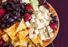 A colorful cheese and fruit platter featuring various cheeses and fresh fruits