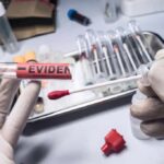 Gloved hands handling a swab and evidence tube