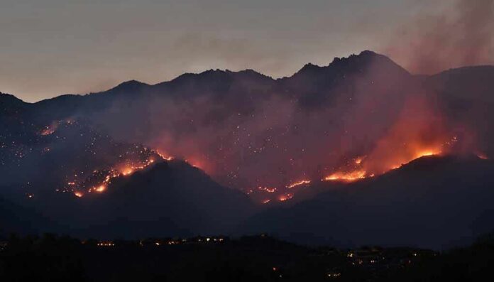 shutterstock_1762464629 Wildfire burning along mountain slopes at dusk