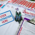 Americans Urged To Stay Vigilant Worldwide Voter registration table with forms, pens, and informational materials