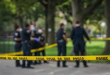 Shots Ring Out Steps From Stadium crime scene tape with police officers in a park