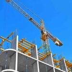Workers Paid Pennies On $350M Build Tower crane over concrete building under construction