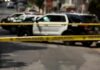 Police tape cordoning off street with patrol SUVs behind