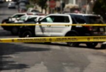Police tape cordoning off street with patrol SUVs behind