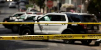 Police tape cordoning off street with patrol SUVs behind