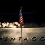 Ground Zero Mic Rules Force Trump Shift Small American flag on a memorial with bokeh lights at night