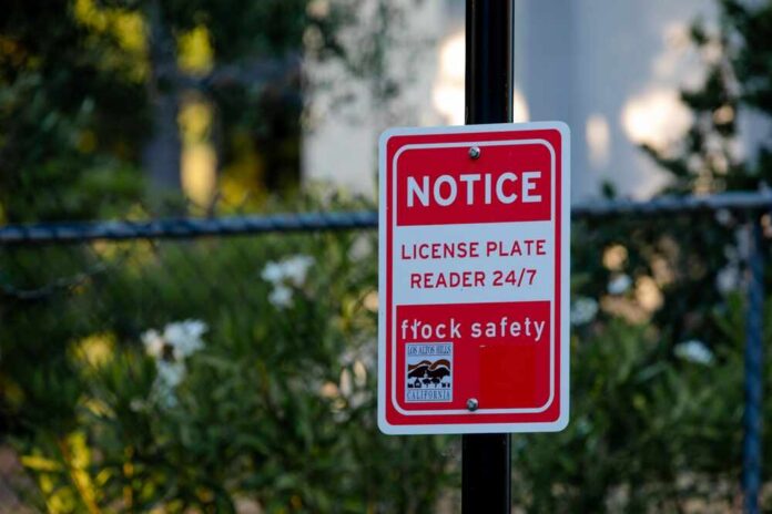 Red notice sign on a black pole in a leafy outdoor area