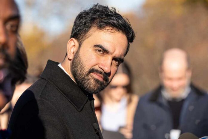Man in a dark coat outdoors looking toward the camera