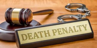 Gavel, handcuffs, and a nameplate reading death penalty on a wooden desk