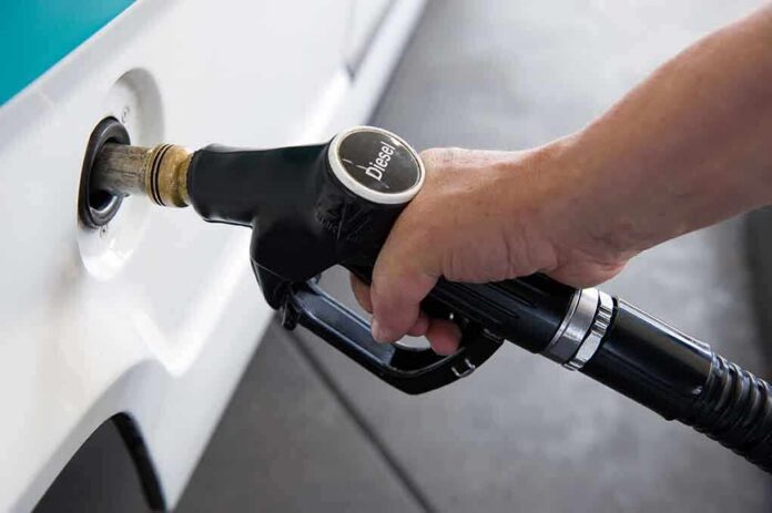 A hand holding a diesel fuel nozzle while refueling a vehicle