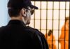 Security guard watching inmates behind jail bars
