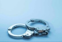 Football Night Turns Felony Fast Metal handcuffs on a light blue surface