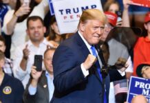 Donald Trump at a rally raising his fists on stage