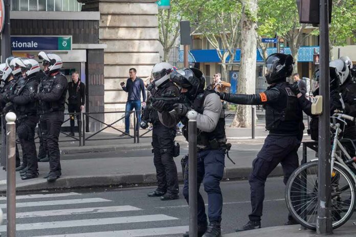 Riot police in helmets line a city street during an operation