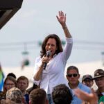 Kamala Harris speaking at outdoor rally, Paul Scholes in the crowd