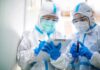 Plague Fears Trigger Lockdown Two healthcare workers in full PPE reviewing a clipboard