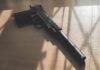 Black pistol with suppressor on wooden table