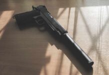 Black pistol with suppressor on wooden table