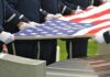 Honor guard holding an American flag over a casket