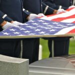 Honor guard holding an American flag over a casket
