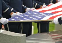 Honor guard holding an American flag over a casket