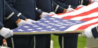 Honor guard holding an American flag over a casket