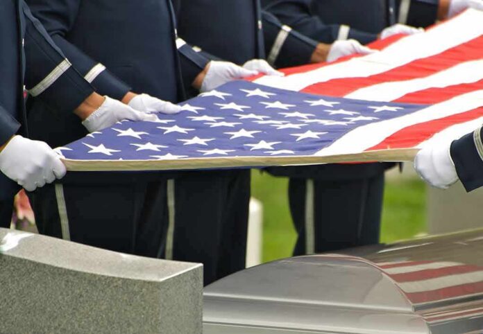 Honor guard holding an American flag over a casket