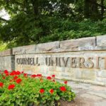 Cornell University stone entrance sign with red flowers